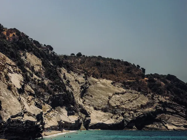 Turquoise baai met zwemmers onder witte kliffen aan de Albanese Rivièra