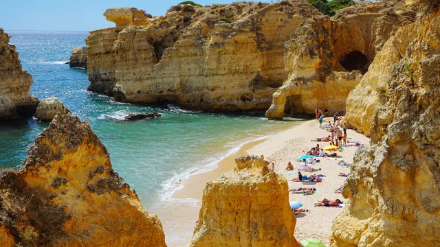 Zandbaai tussen goudgele kliffen aan de Algarve met badgasten op het strand