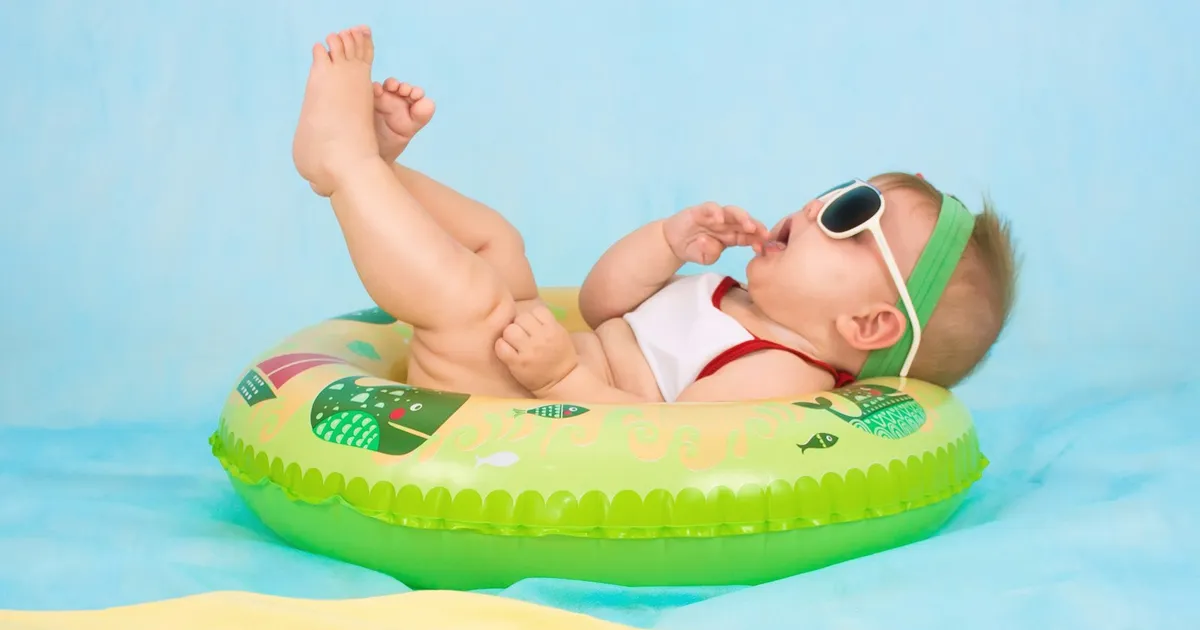 Baby met zonnebril relaxt in een groene zwemband