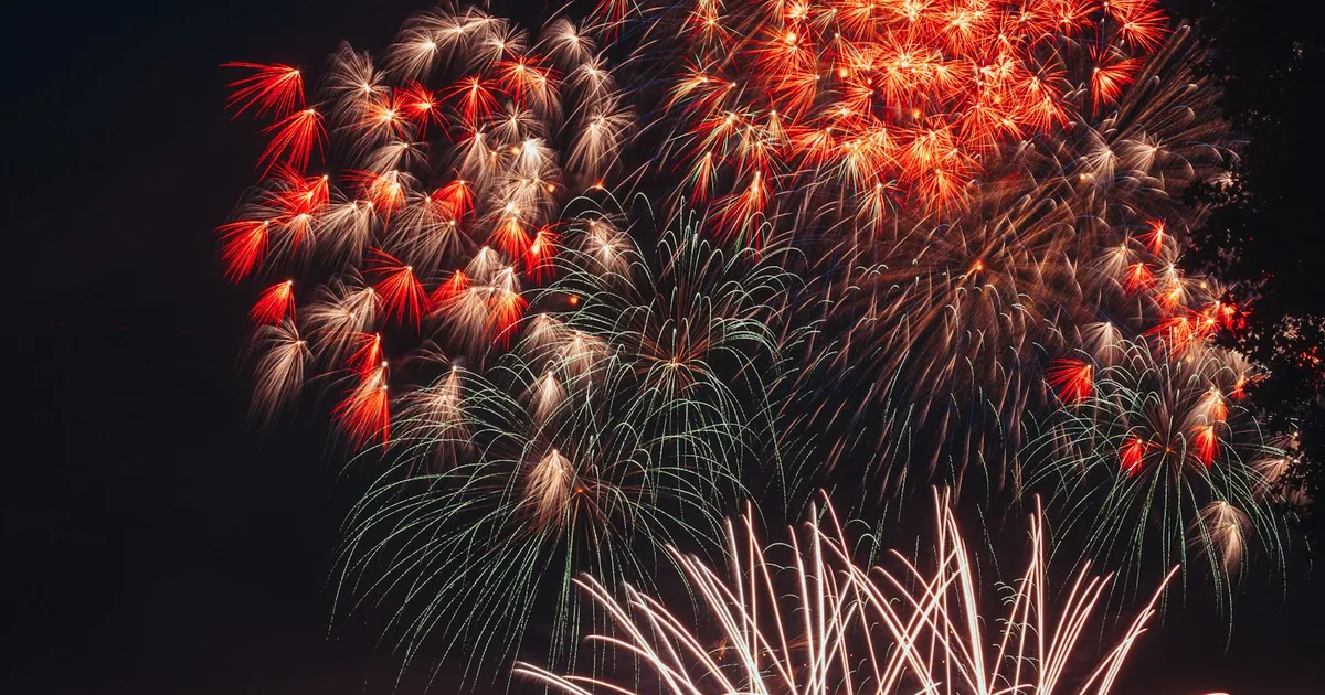 Groot vuurwerk boven een baai met boten en toeschouwers