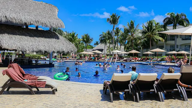 Druk maar verzorgd resortzwembad met rieten parasols en ligbedden