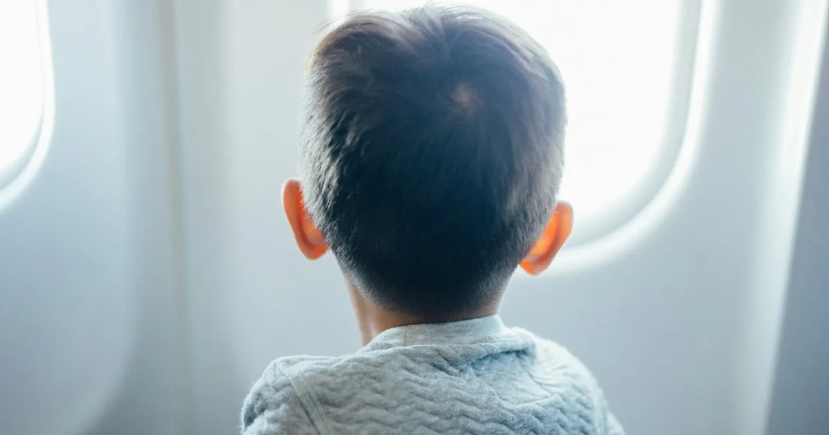 Jongetje kijkt door het raam van een vliegtuig naar buiten