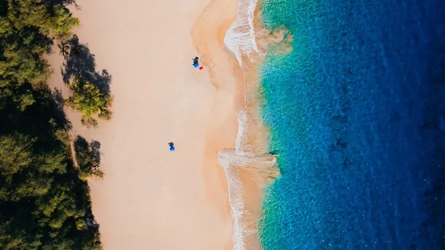 Luchtfoto van een verlaten zandstrand met turquoise zee en groene bomen