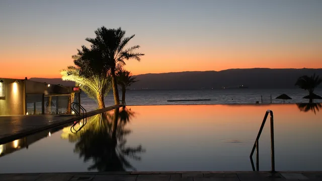 Infinity pool met palmen aan zee tijdens zonsondergang