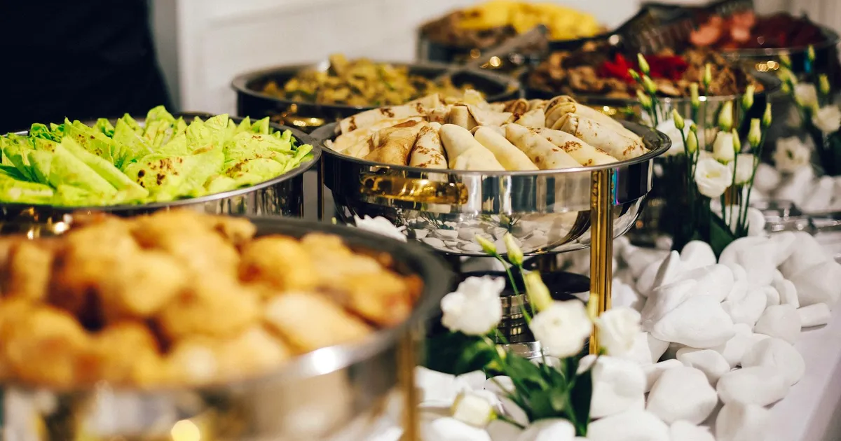 Buffet met verse gerechten in zilveren schalen en verse bloemen