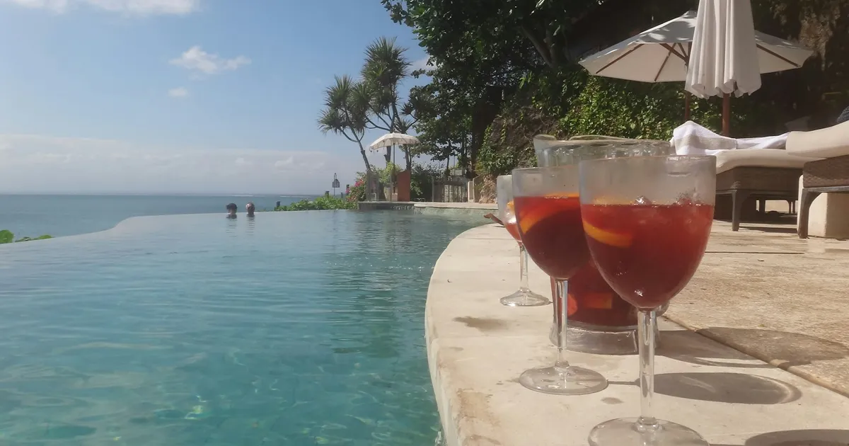 Cocktails op de rand van een infinity pool met zee op de achtergrond
