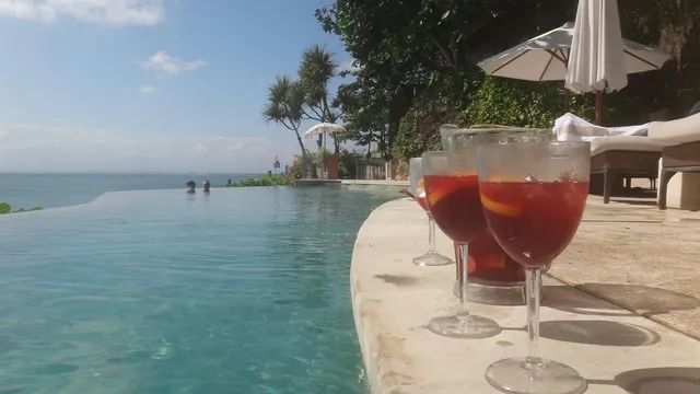 Cocktails op de rand van een infinity pool met zee op de achtergrond