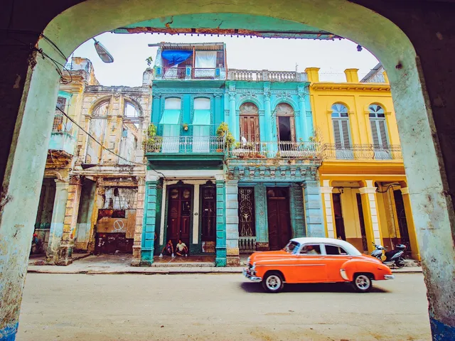 Oranje oldtimer rijdt langs kleurrijke koloniale gevels in Havana