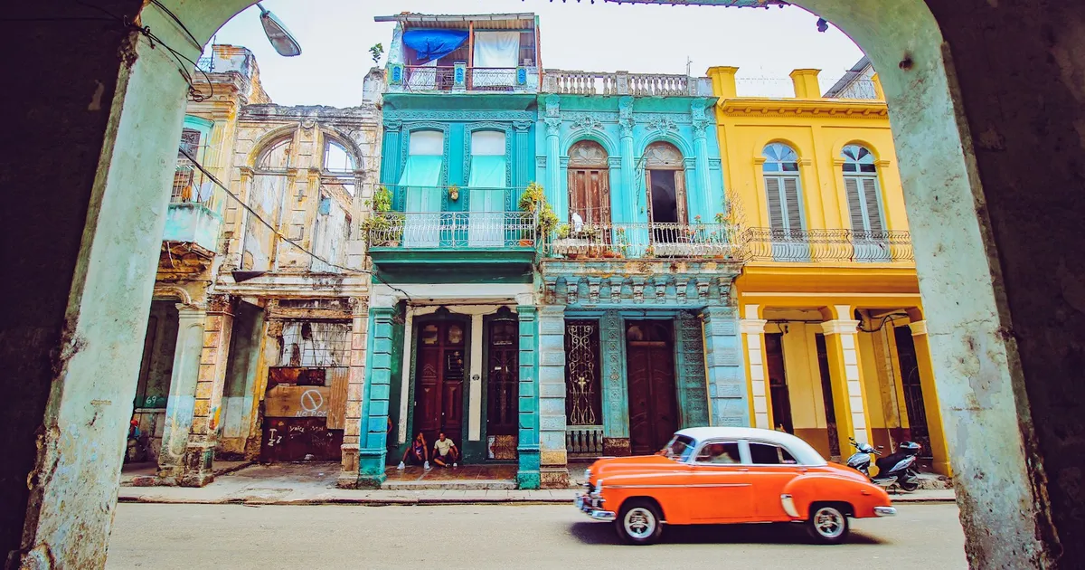 Oranje oldtimer rijdt langs kleurrijke koloniale gevels in Havana