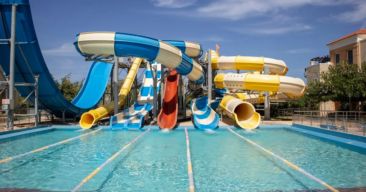 Kleurrijke waterglijbanen in een aquapark onder een blauwe lucht
