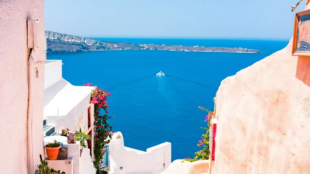 Wit trapstraatje met roze bougainvillea en zeezicht op Santorini