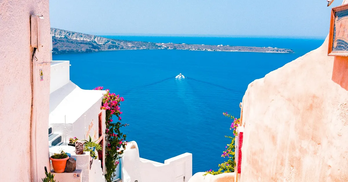 Wit trapstraatje met roze bougainvillea en zeezicht op Santorini