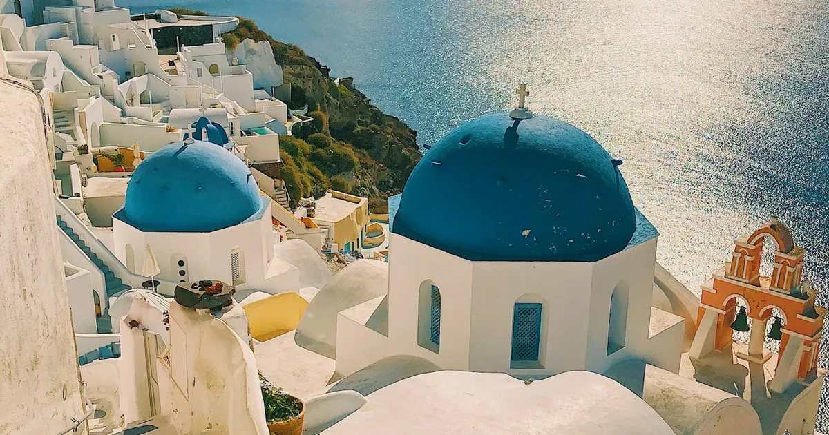Witte huizen en blauwe koepels van Oia op Santorini met zeezicht