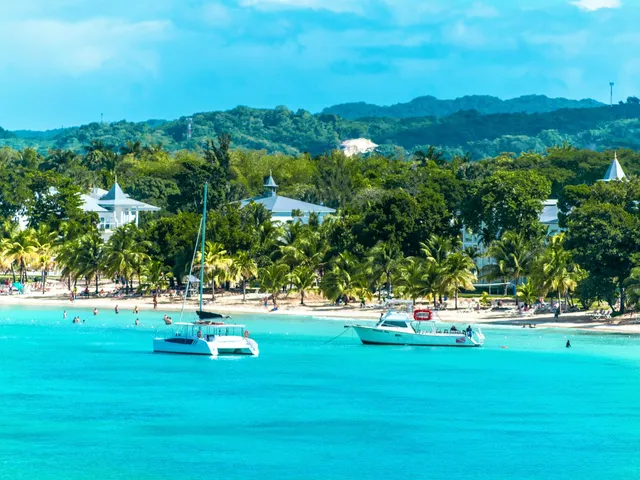 Turquoise baai bij Negril met catamarans, palmen en groene heuvels