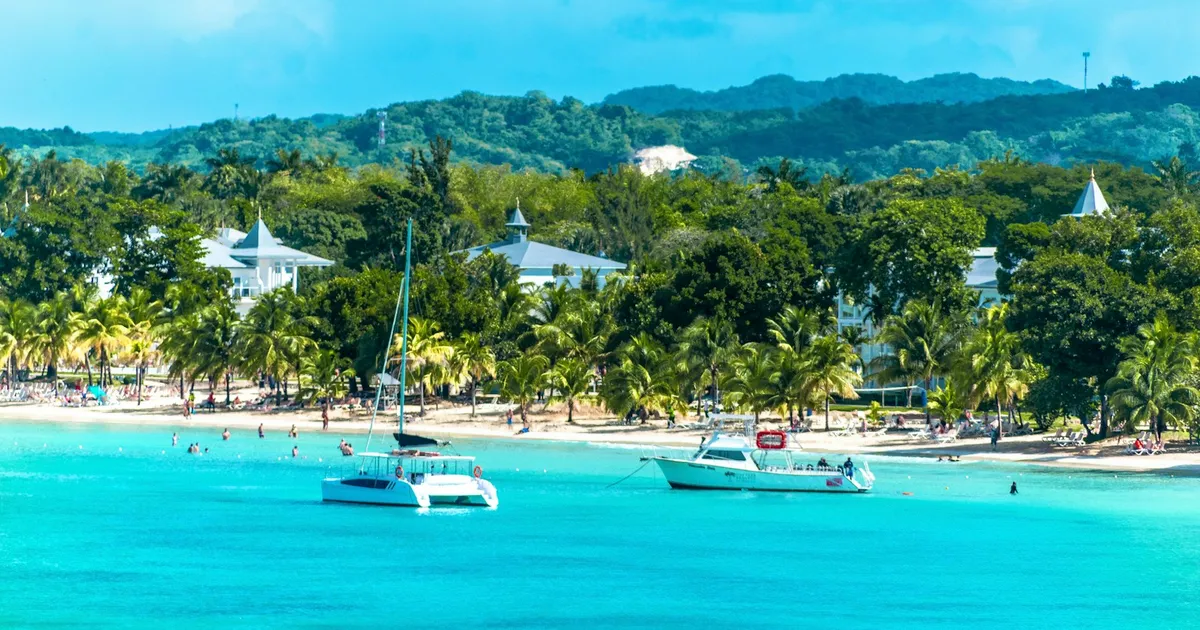 Turquoise baai bij Negril met catamarans, palmen en groene heuvels