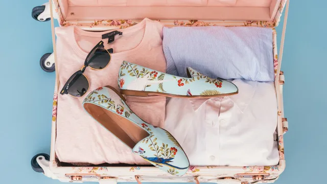 Open koffer met zomerkleding, zonnebril en schoenen, klaar om in te pakken