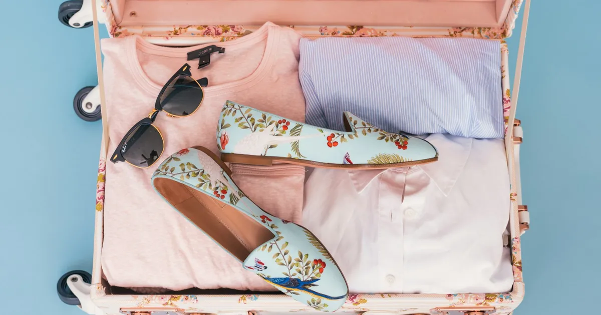 Open koffer met zomerkleding, zonnebril en schoenen, klaar om in te pakken