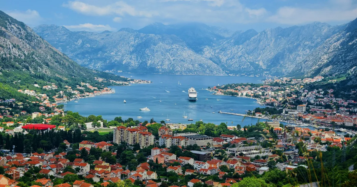 De baai van Kotor met bergen, rode daken en een cruiseschip van bovenaf