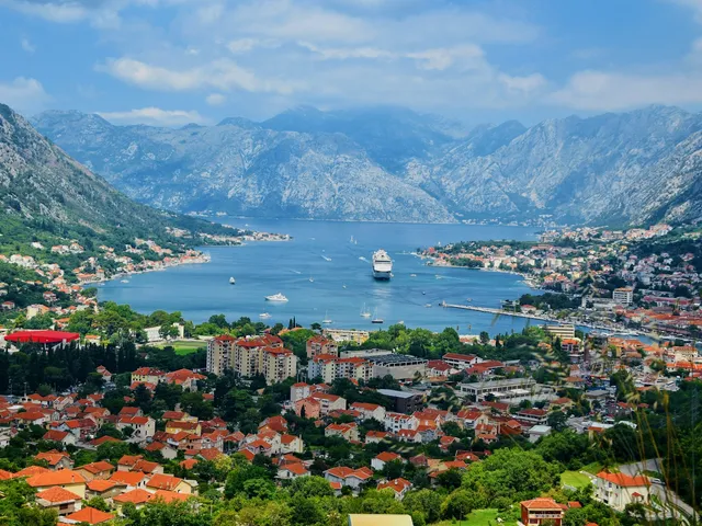 De baai van Kotor met bergen, rode daken en een cruiseschip van bovenaf