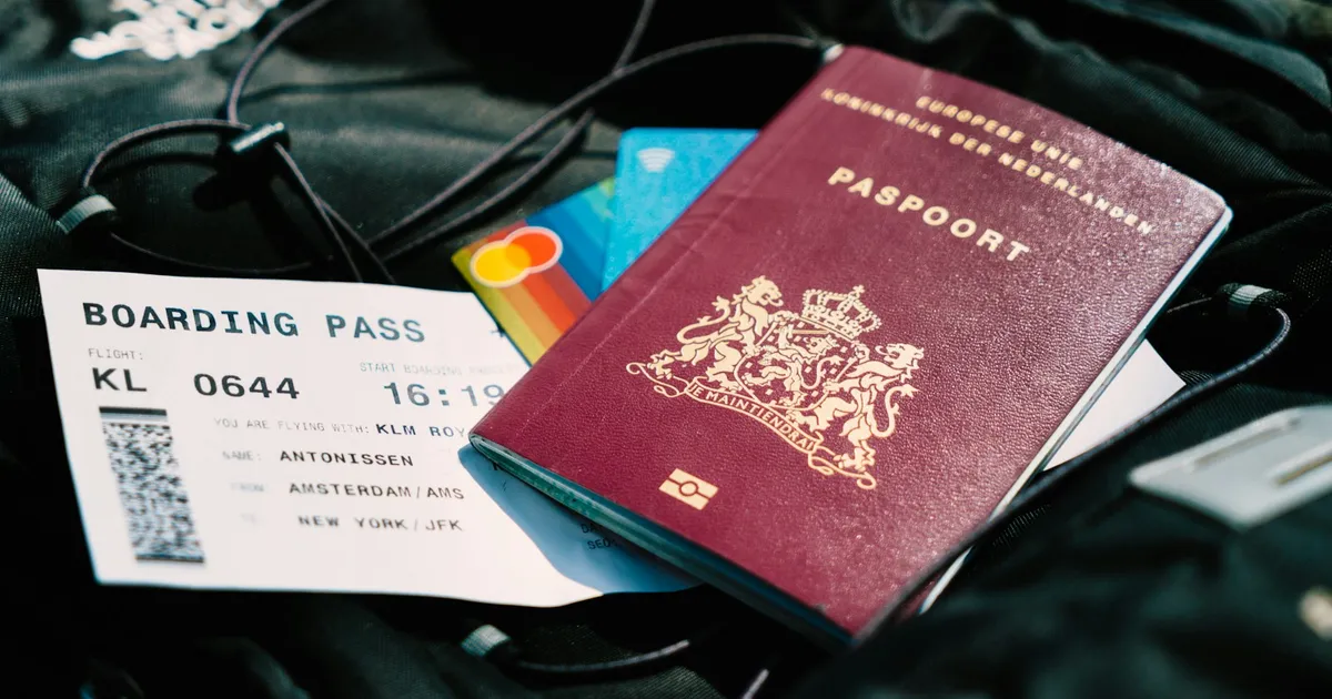 Nederlands paspoort met instapkaart en bankpassen op een reistas
