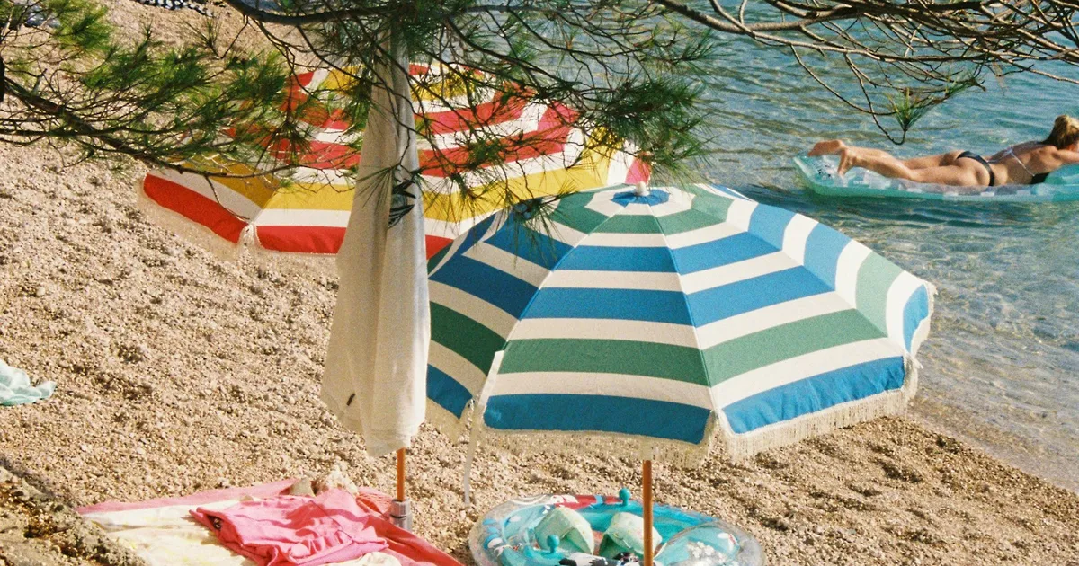 Kleurrijke parasols op een kiezelstrand aan helder zeewater