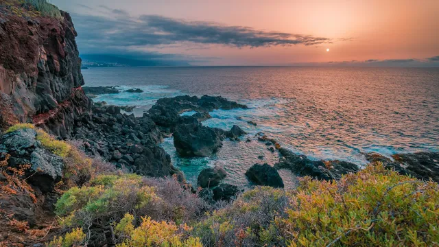Rotsachtige kust van Tenerife met herfstkleurige struiken bij zonsondergang