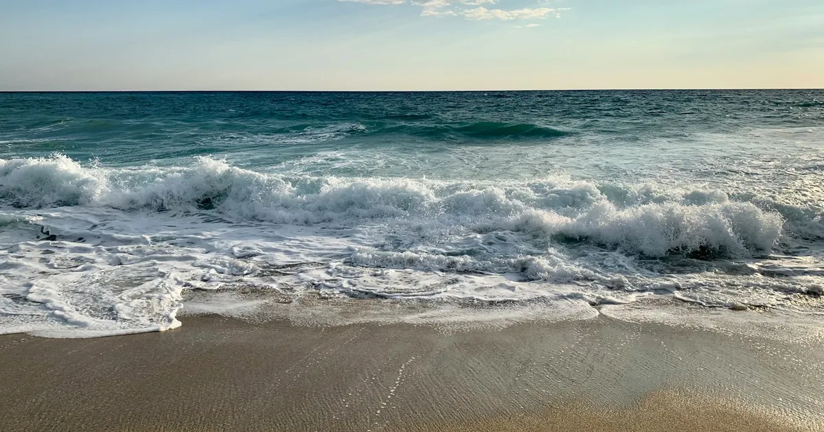 Golven rollen op het brede zandstrand van Alanya