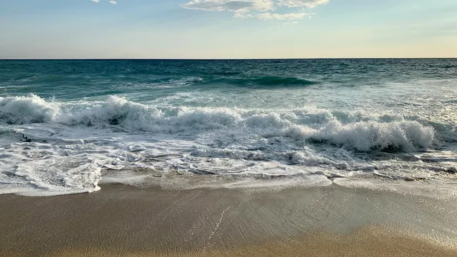 Golven rollen op het brede zandstrand van Alanya