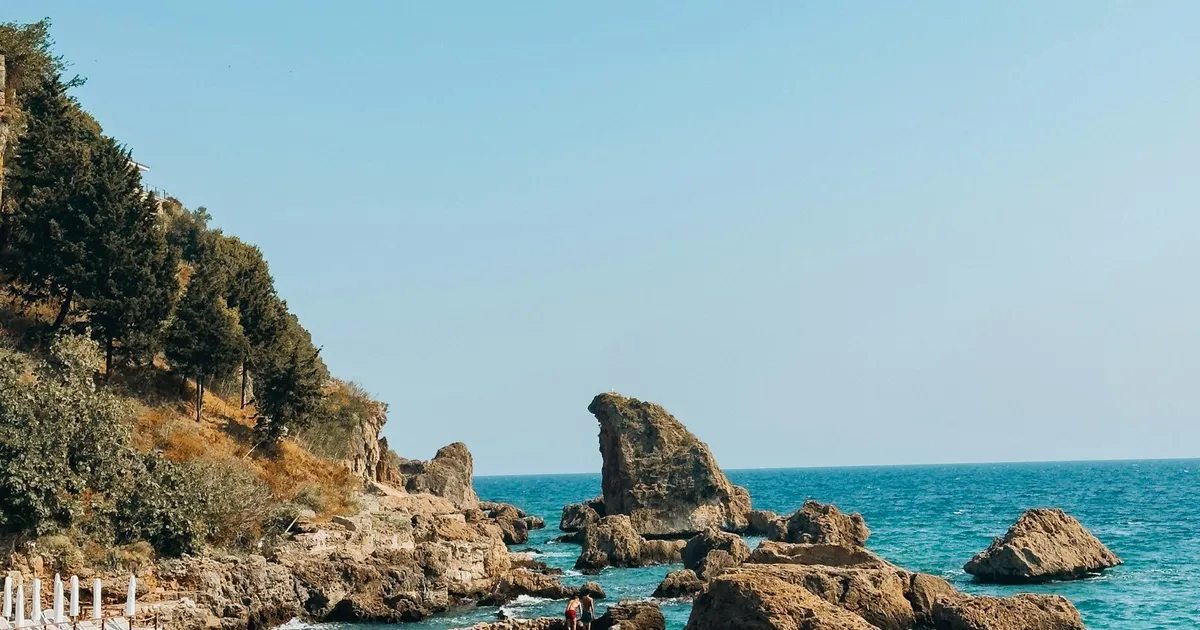 Turquoise zee met rotsen en parasols aan de kust van Antalya