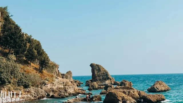 Turquoise zee met rotsen en parasols aan de kust van Antalya
