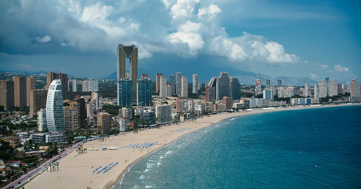 De skyline en het brede zandstrand van Benidorm aan een blauwe baai