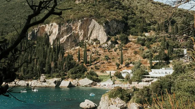 Turquoise baai met kliffen, cipressen en een strandje op Corfu