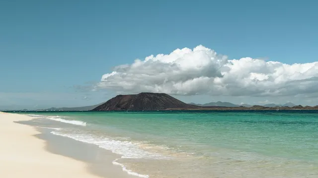 Wit strand met turquoise zee en het eiland Lobos bij Corralejo