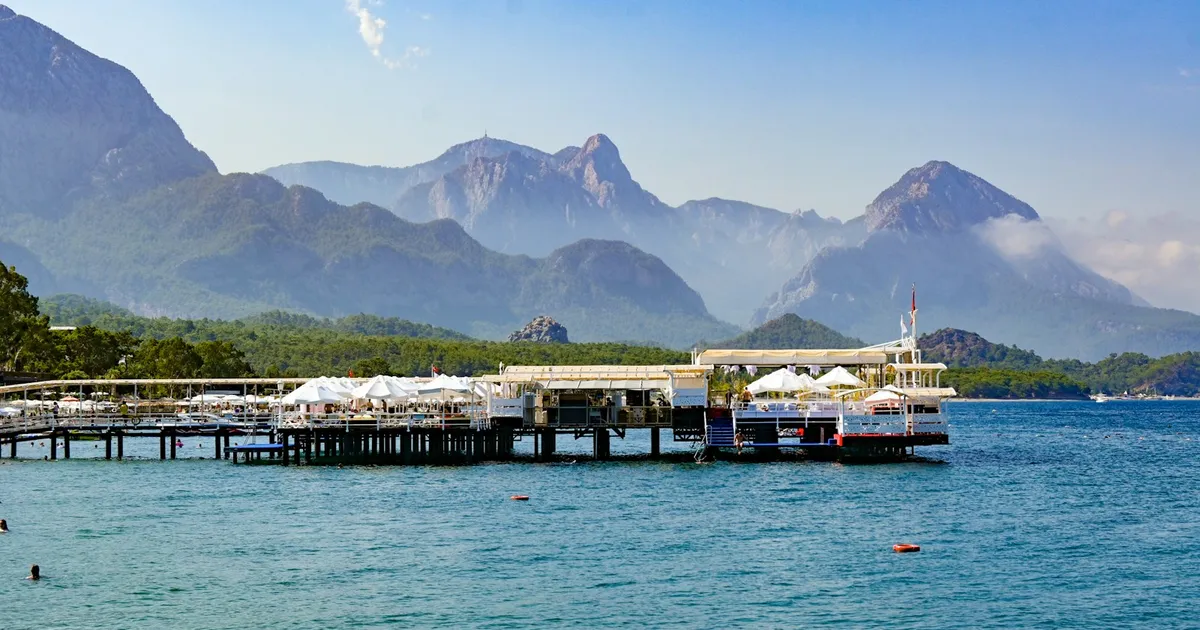 Pier met parasols aan zee bij Kemer met het Taurusgebergte als decor