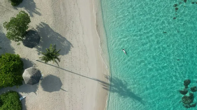 Strand met rieten parasols en helder turquoise zeewater van bovenaf