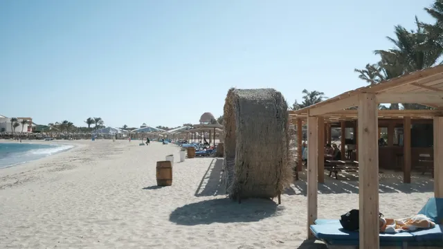 Wit strand met rieten parasols en een strandbar bij Marsa Alam