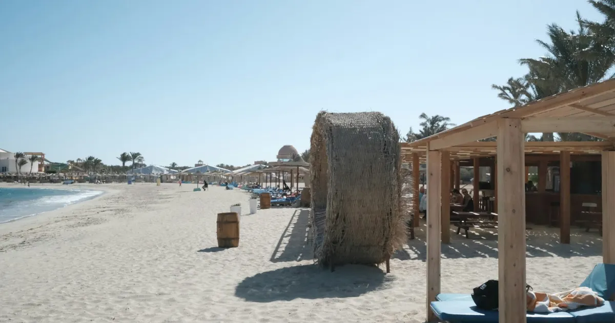 Wit strand met rieten parasols en een strandbar bij Marsa Alam