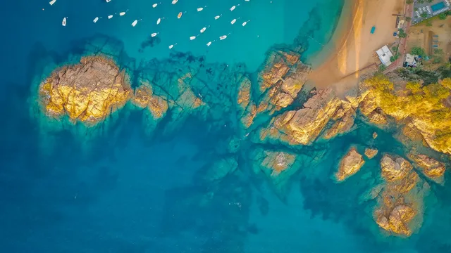 Luchtfoto van een baai met bootjes, rotsen en helder turquoise water