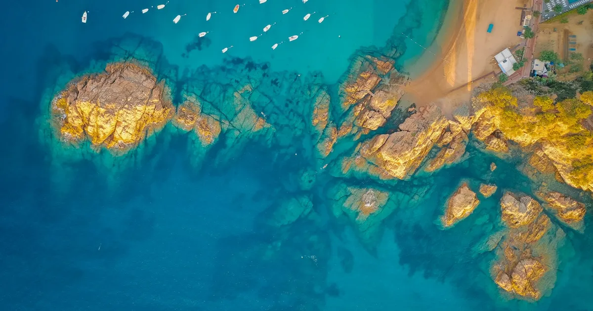 Luchtfoto van een baai met bootjes, rotsen en helder turquoise water
