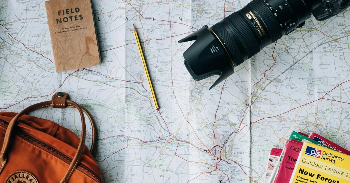 Reiskaart met camera, notitieboekje en rugzak als voorbereiding op vakantie