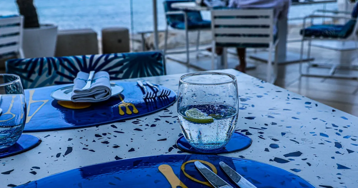 Gedekte restauranttafel met waterglas en uitzicht op zee