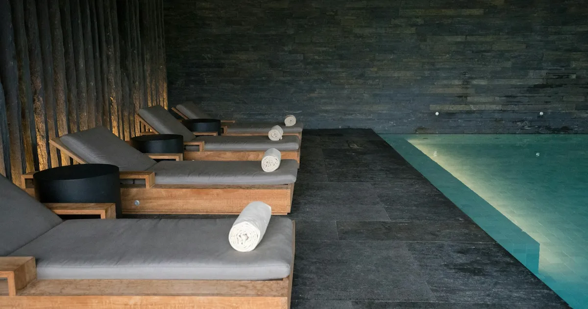 Serene spa-ruimte met ligbedden, opgerolde handdoeken en binnenbad
