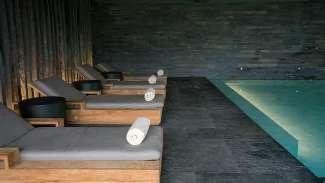 Serene spa-ruimte met ligbedden, opgerolde handdoeken en binnenbad
