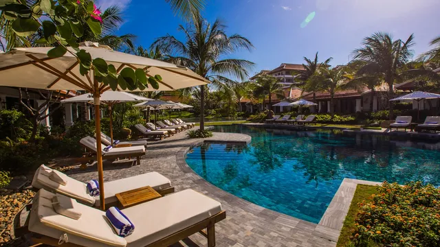 Resortkamers met ligbedden direct aan een zonnig zwembad