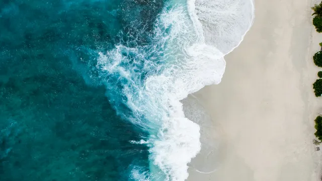 Luchtfoto van turquoise zee met brekende golven op een strand