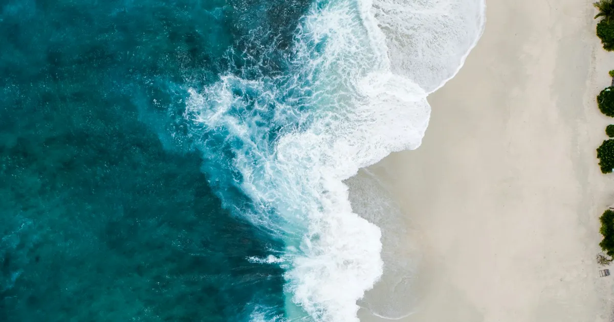 Luchtfoto van turquoise zee met brekende golven op een strand